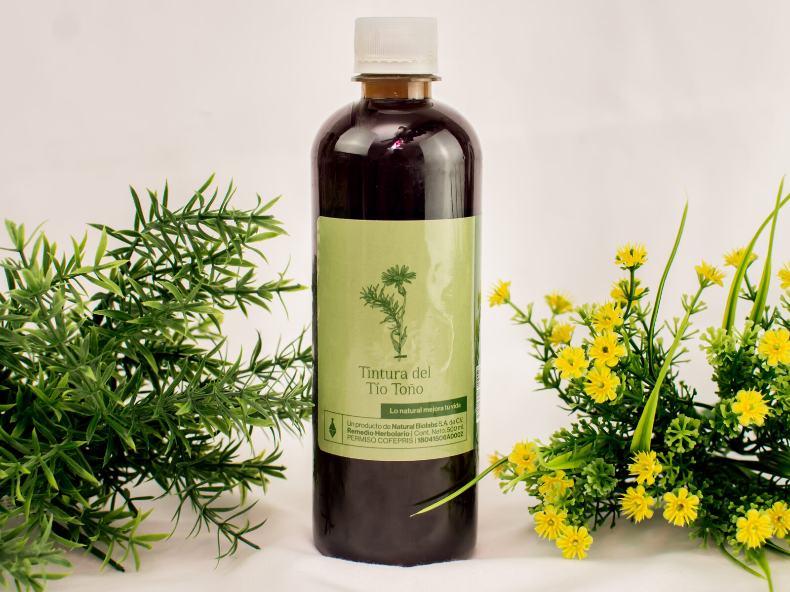 Botella de Tintura del Tío Toño con romero y flores amarillas